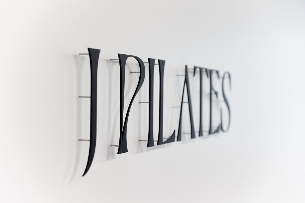 black sign on white wall for J Pilates